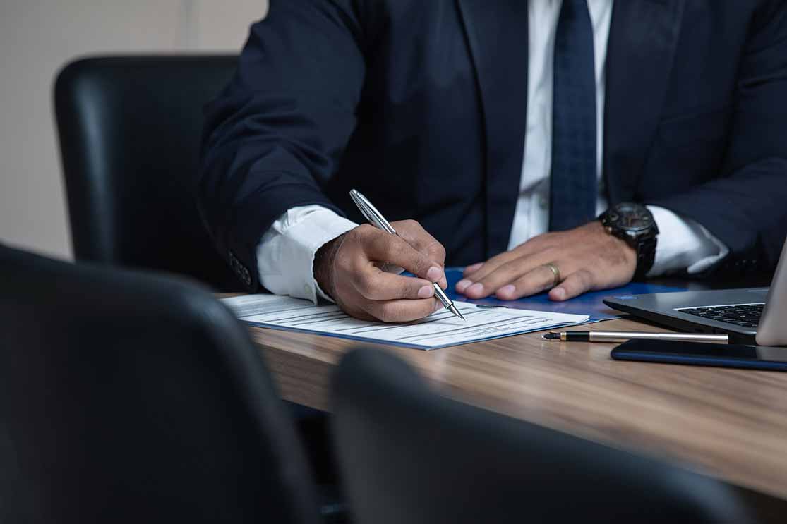 person in a suit signing a document