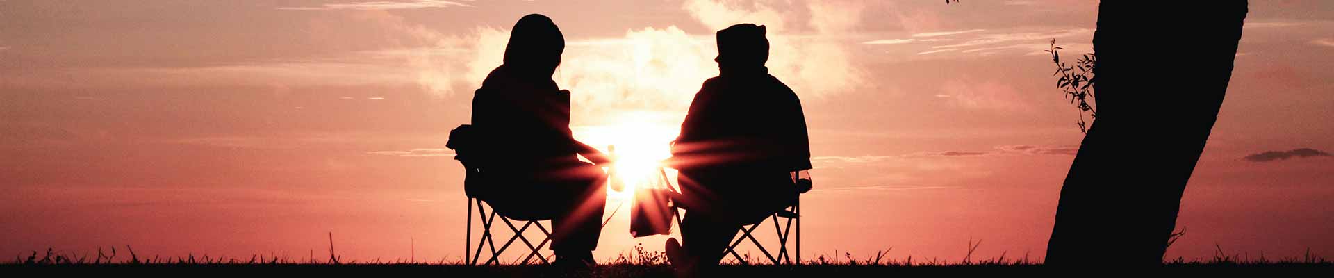 two people sitting in front of a sunset